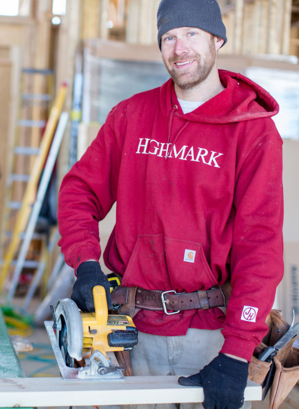 Man in red Highmark hooded sweatshirt and circular saw cutting a board.