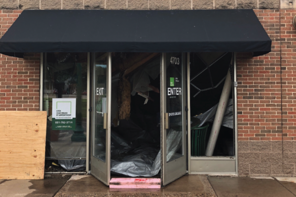The front door of a commercial business with a black awning undergoing restorations.
