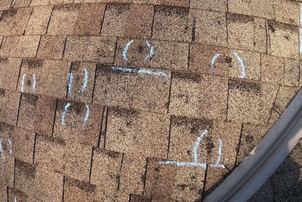 Roof hail damage, storm damage repair needed on roof shingles. Chalk marks indicate repairs needed after storm damage restoration.